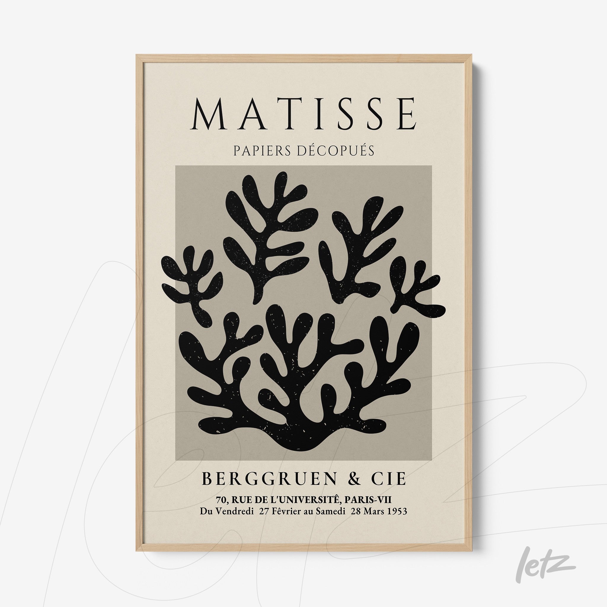 framed wall art featuring black and white cut-out leaves with a light wood frame