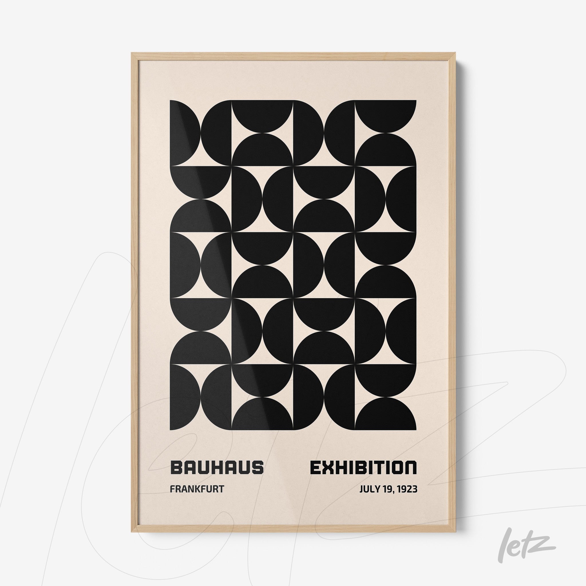 framed artwork featuring black geometric pattern and text about bauhaus exhibition with light wood frame