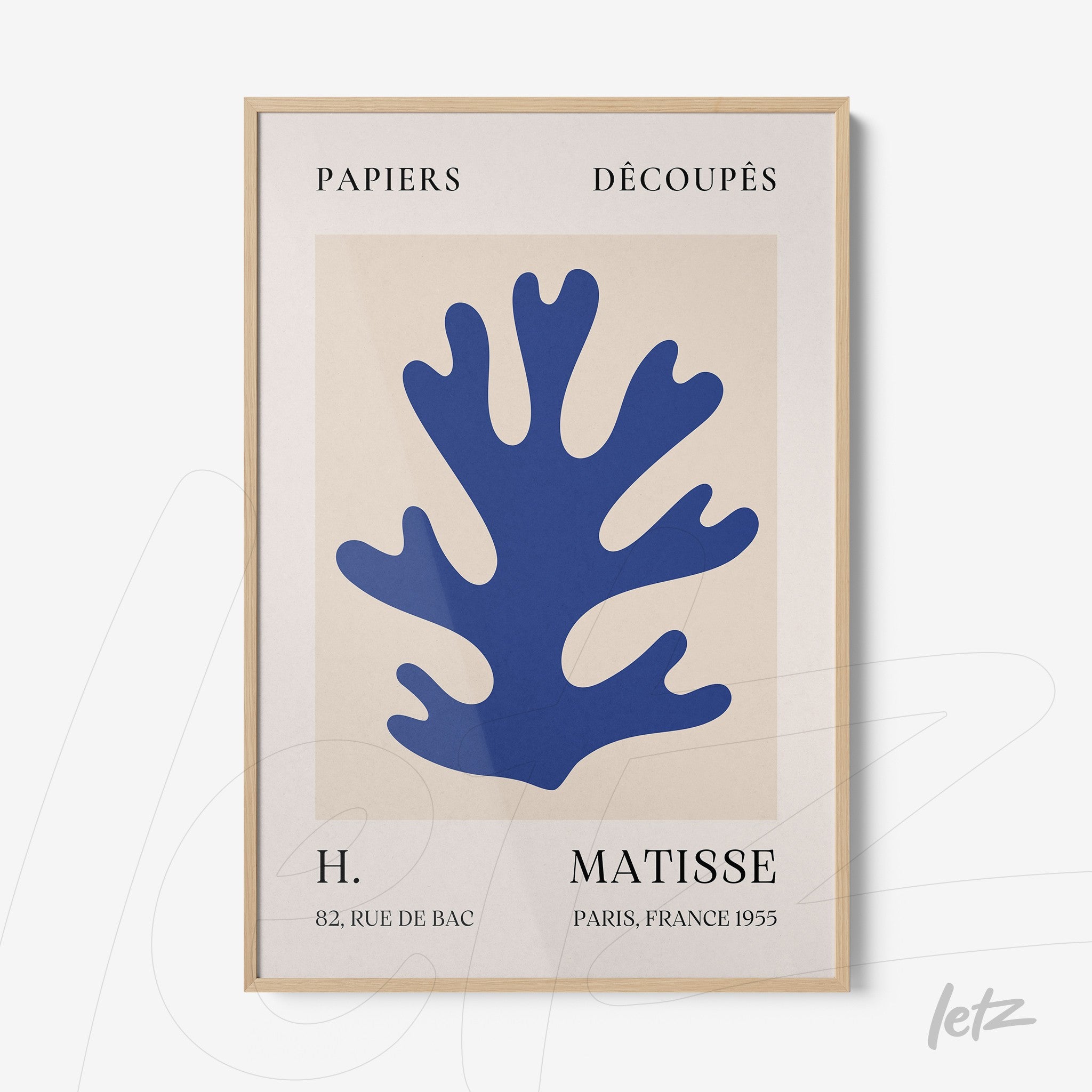 framed art print featuring blue paper cutouts on cream background with light wood frame