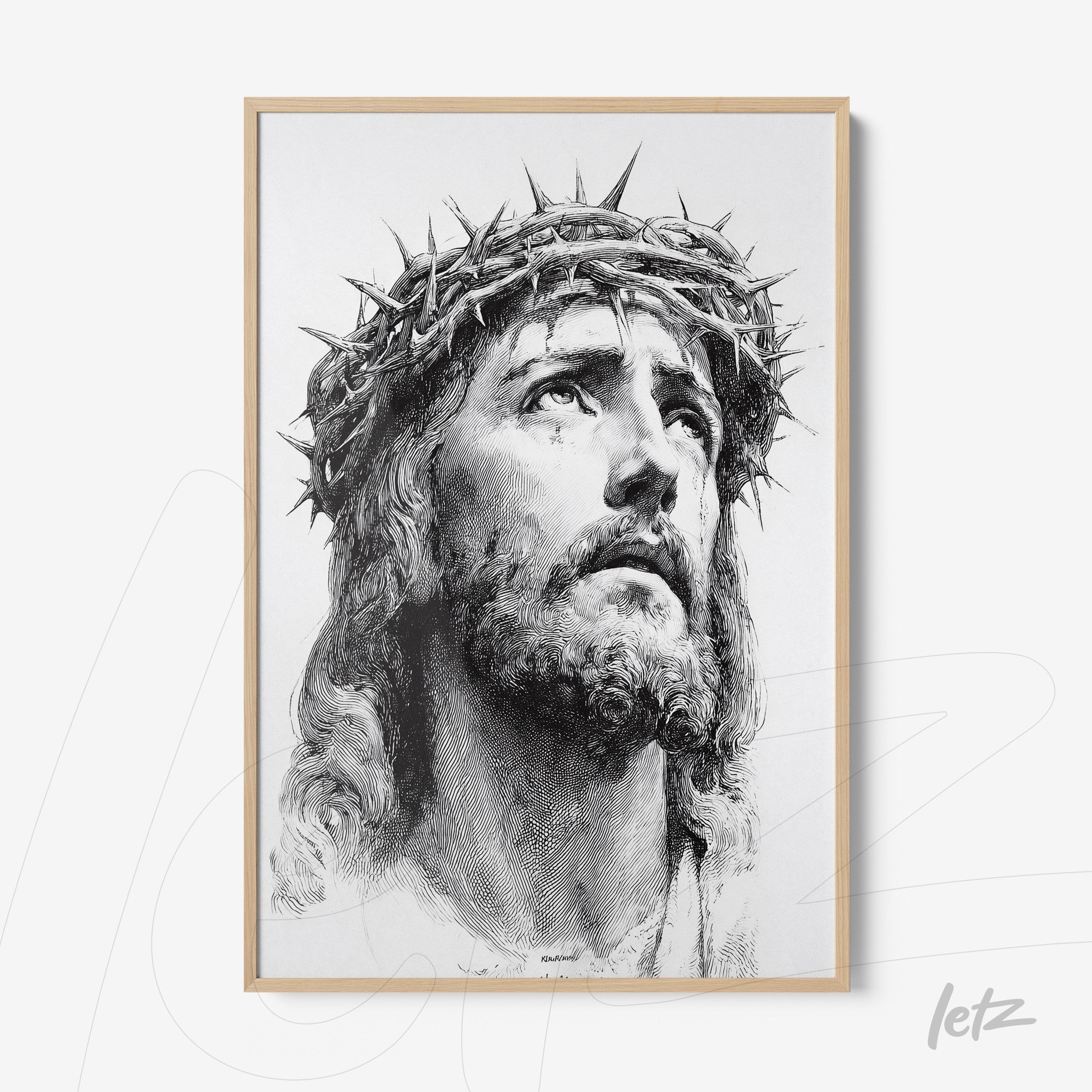 framed black and white artwork depicting the face of Jesus with a crown of thorns in a light wood frame