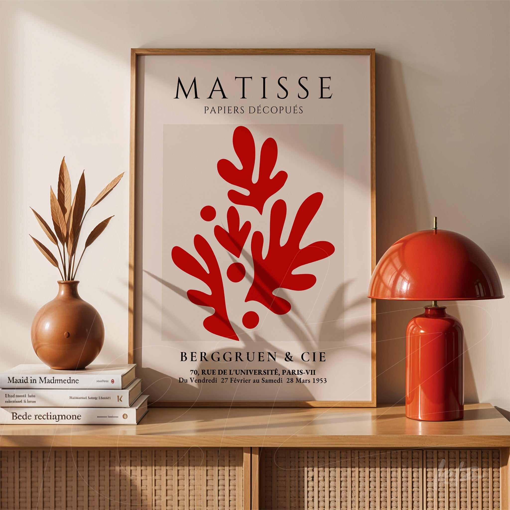wall art featuring cut-out style inspired by Matisse in light wood frame displayed on a wooden sideboard with a ceramic vase and red lamp