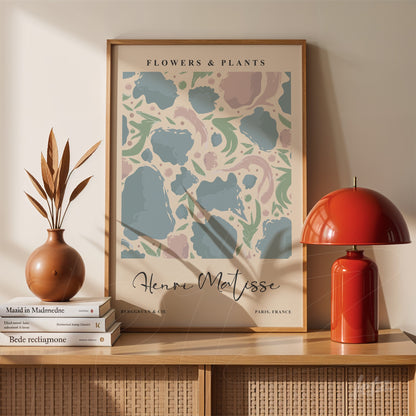 framed wall art featuring modern illustration of flowers and plants in light frame, displayed on wooden shelf with vase and lamp