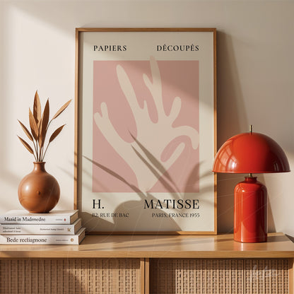 framed modern art featuring abstract shapes on soft pink background with light wood frame