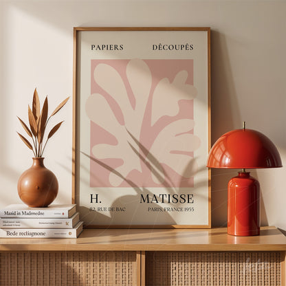 framed modern artwork by Henri Matisse displayed on wooden table with a plant vase