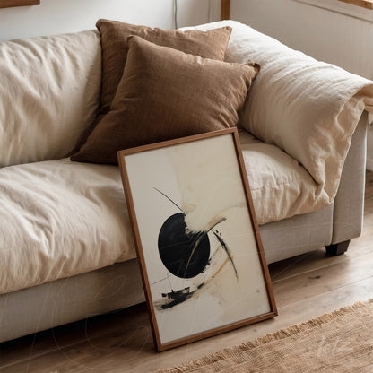 abstract artwork featuring fluid shapes on a light background in a light wood frame leaning against a beige sofa with brown cushions