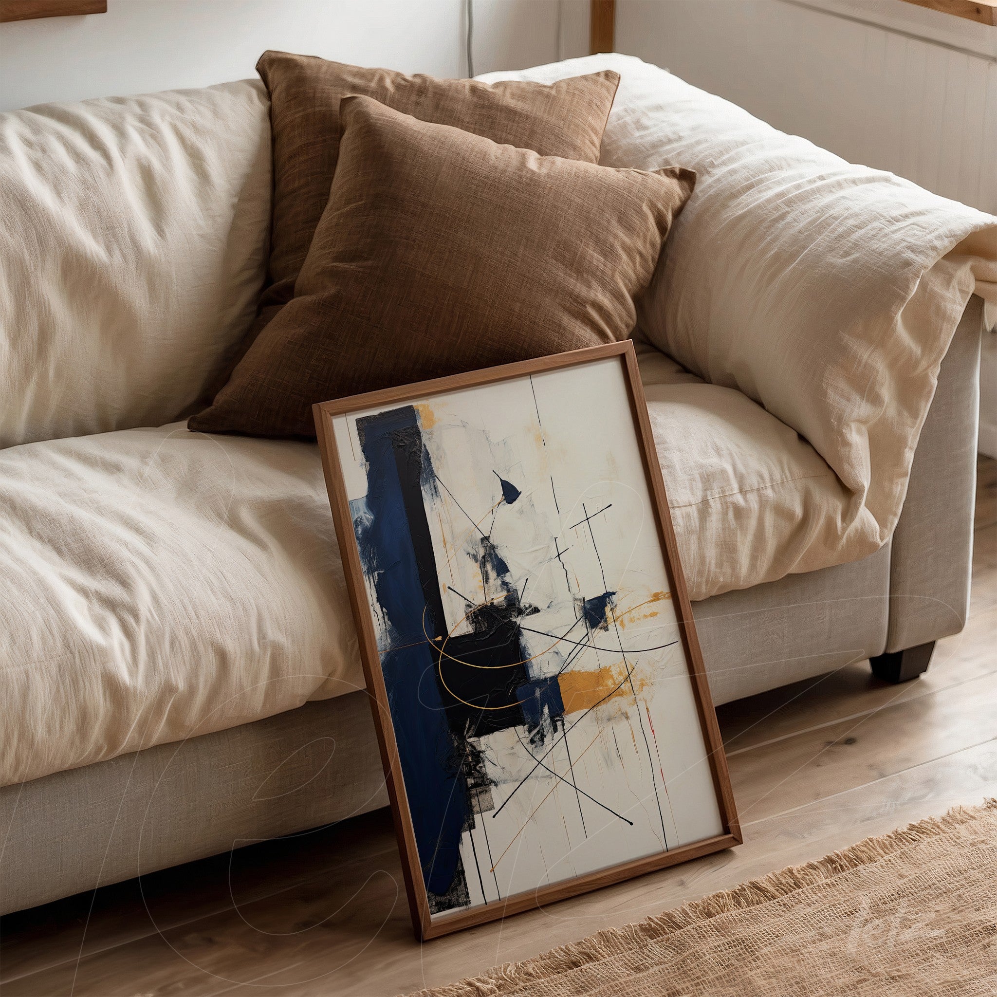 framed abstract art in shades of blue and yellow leaning against a light sofa with brown cushions