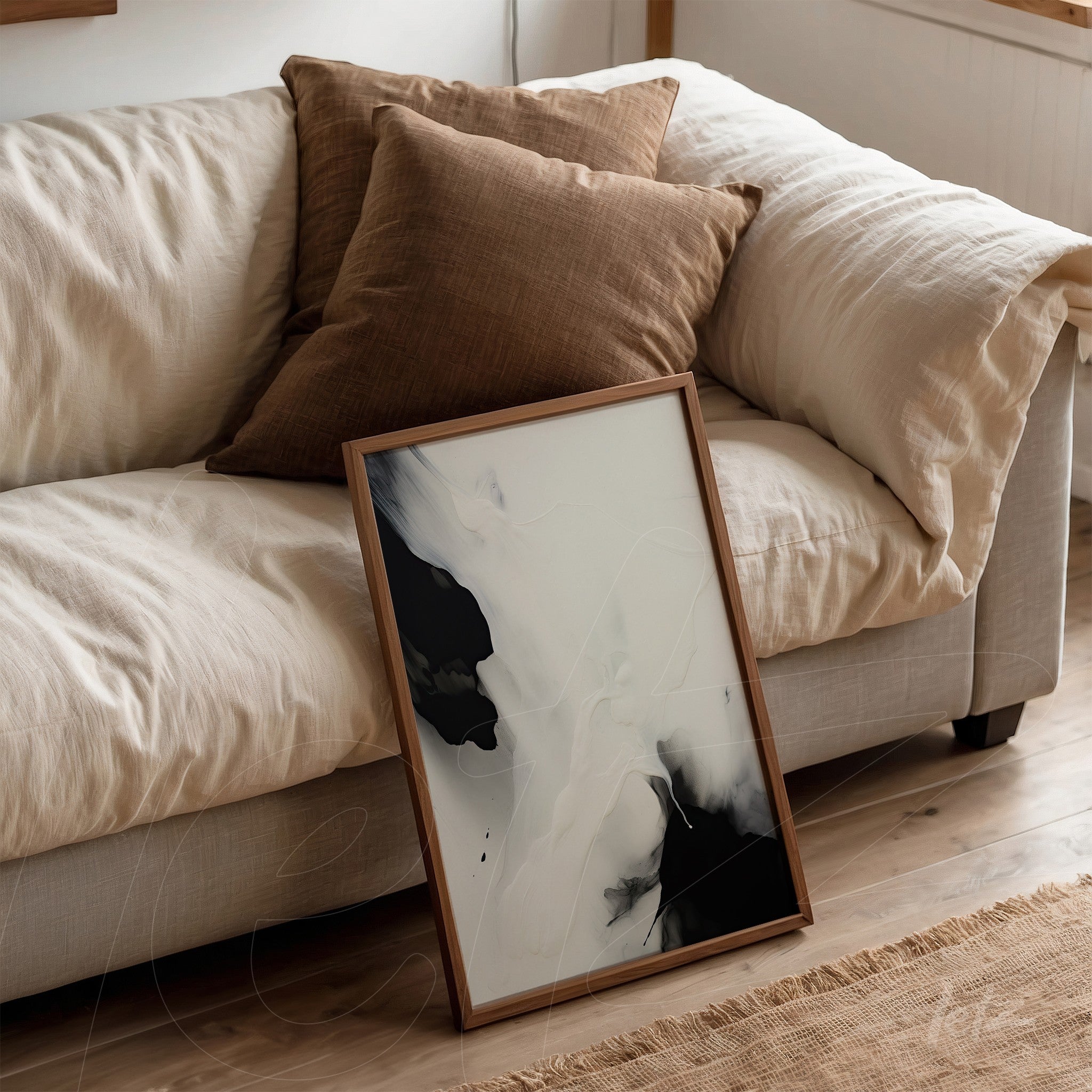 abstract wall art in black and white propped against a sofa with brown cushions