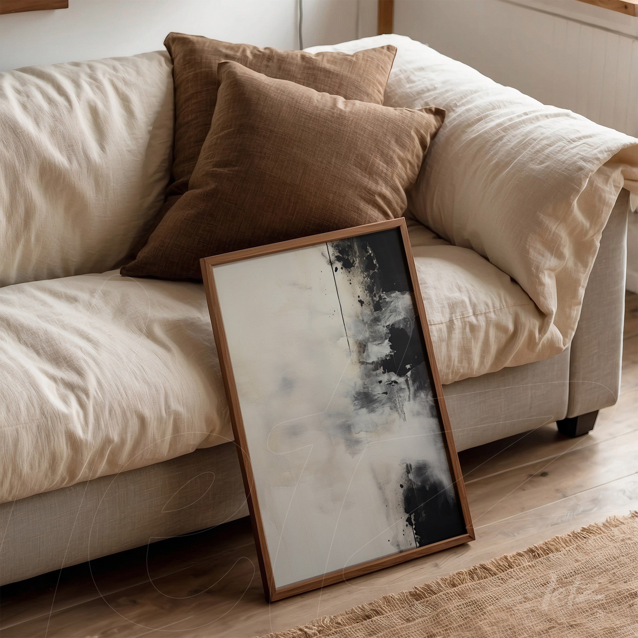 framed abstract wall art in black and white with light wood frame leaning against a light fabric sofa with brown cushions
