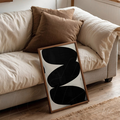 abstract wall art in black and white leaning against a neutral sofa with light wood frame