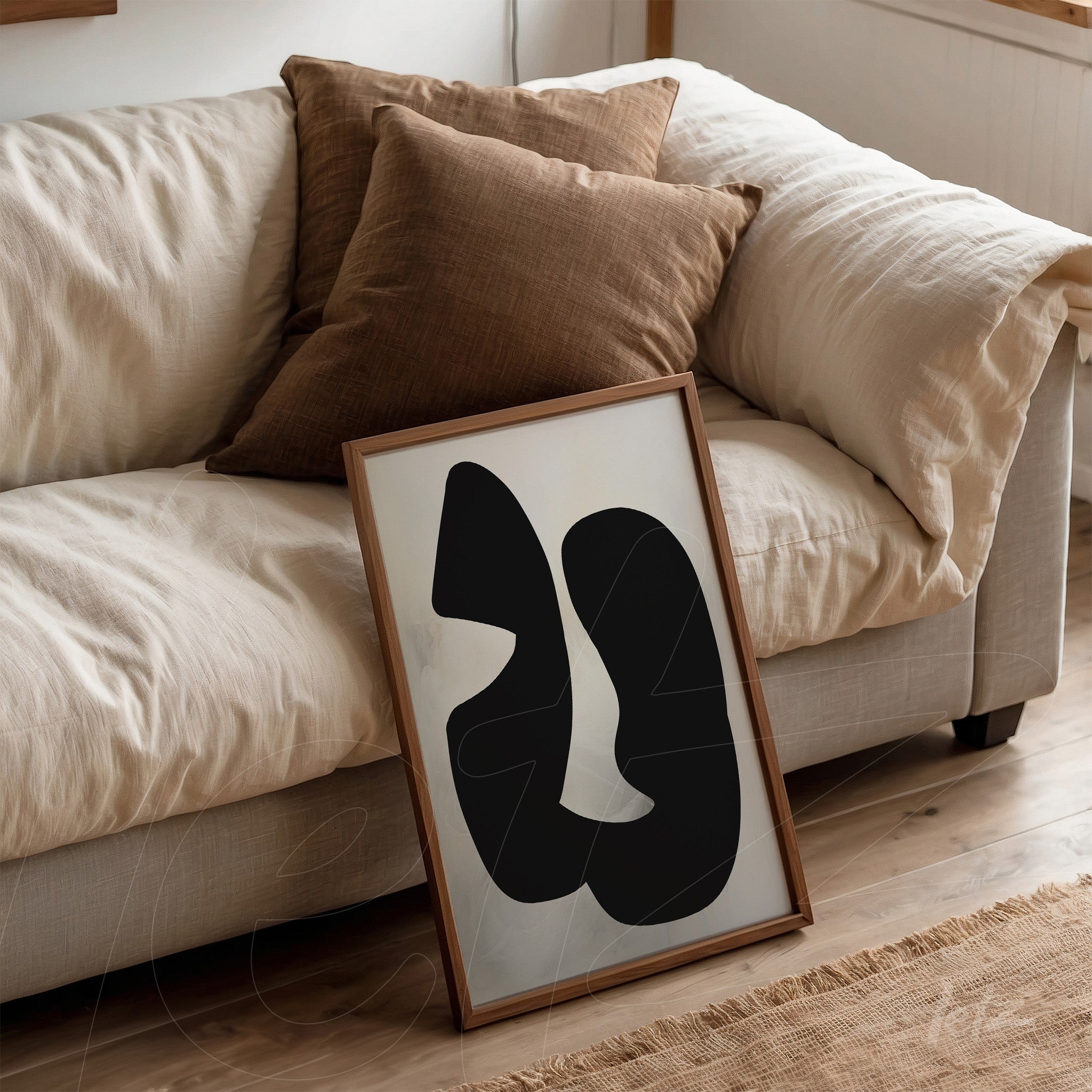 abstract wall art in black and white leaning against a beige sofa with brown cushions