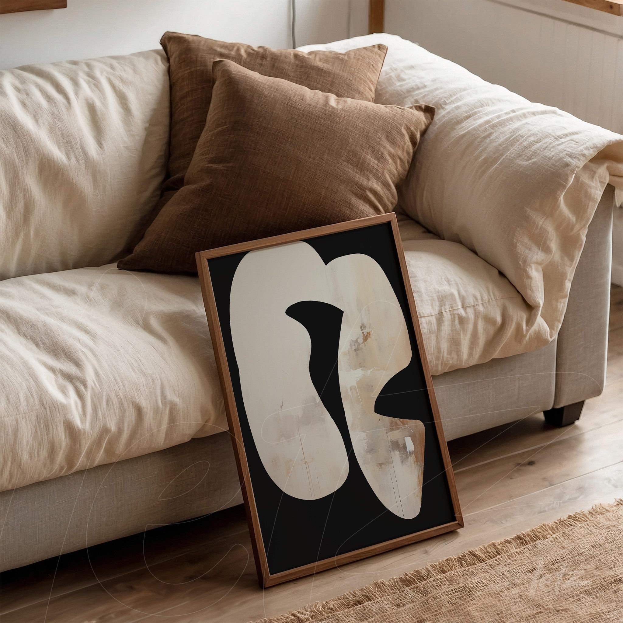 modern artwork featuring abstract shapes on a black background with a wooden frame, leaning beside cushions on a light sofa