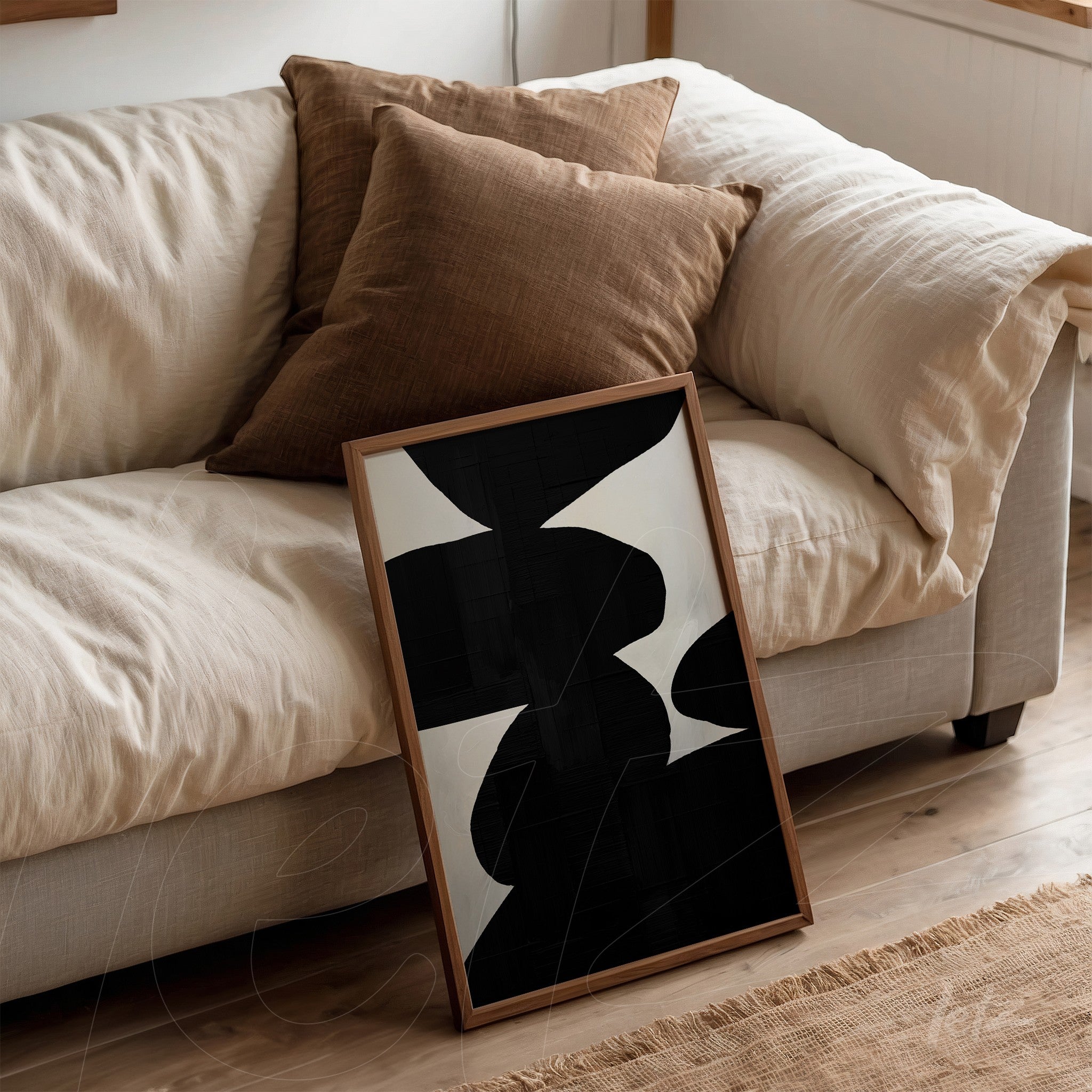 abstract wall art in black and white leaning against a beige sofa with brown cushions