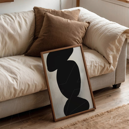minimalist artwork featuring abstract black shapes, leaning against a sofa with brown cushions
