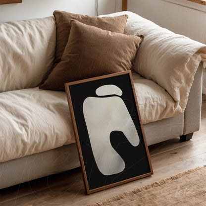 abstract wall art in black background, light wood frame, leaning against a sofa with brown cushions
