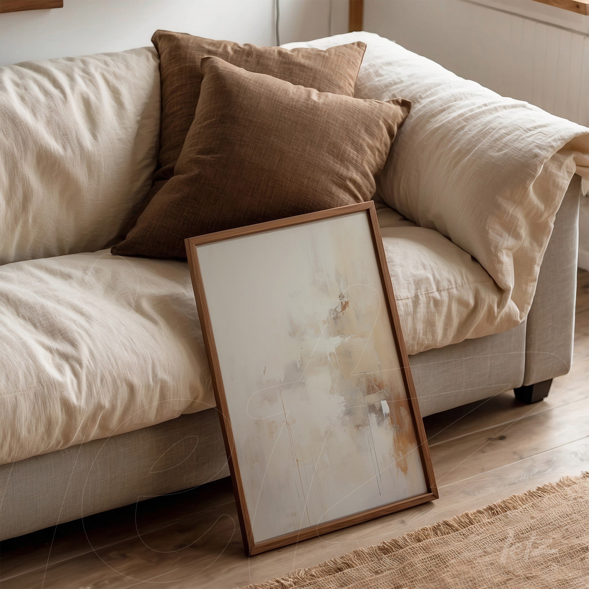 framed wall art featuring abstract design in neutral tones resting against a sofa with brown cushions