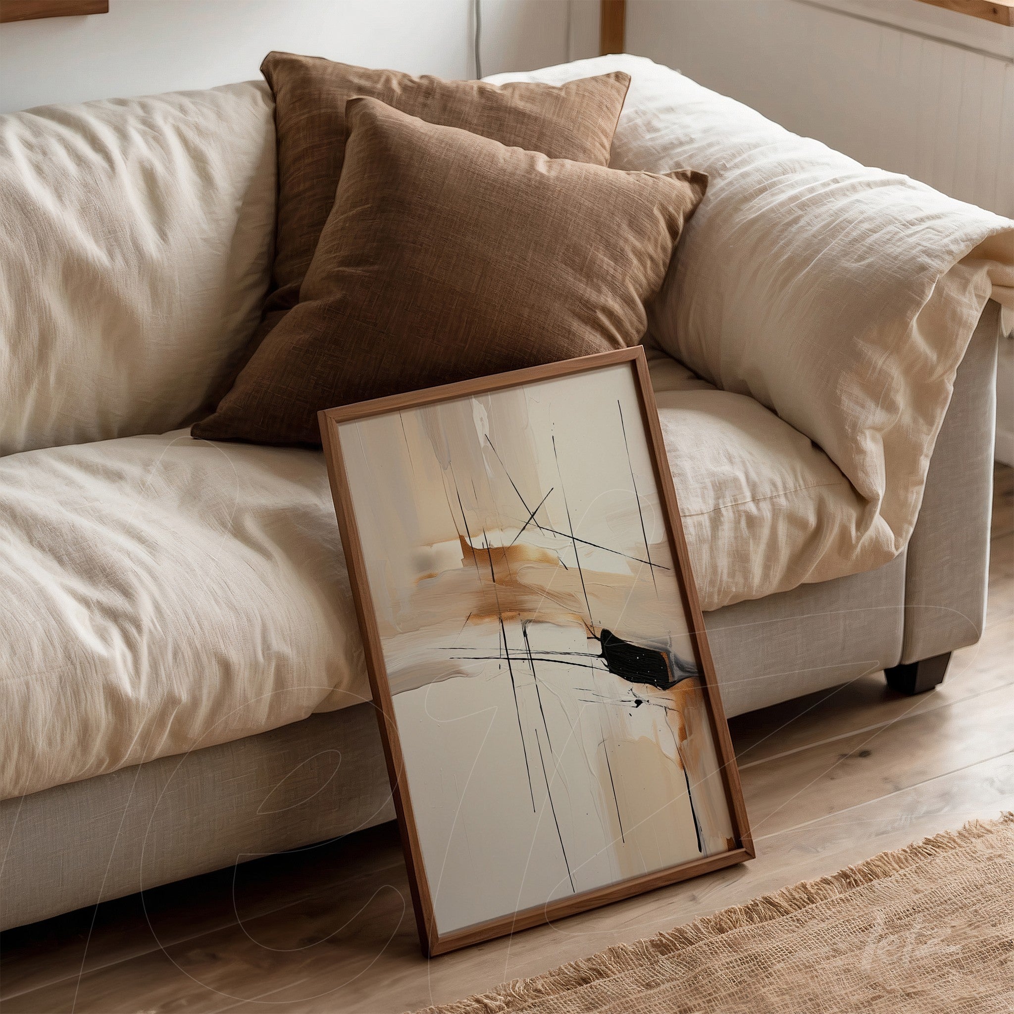 framed abstract art in earthy tones with black strokes, leaning next to pillows on a light sofa