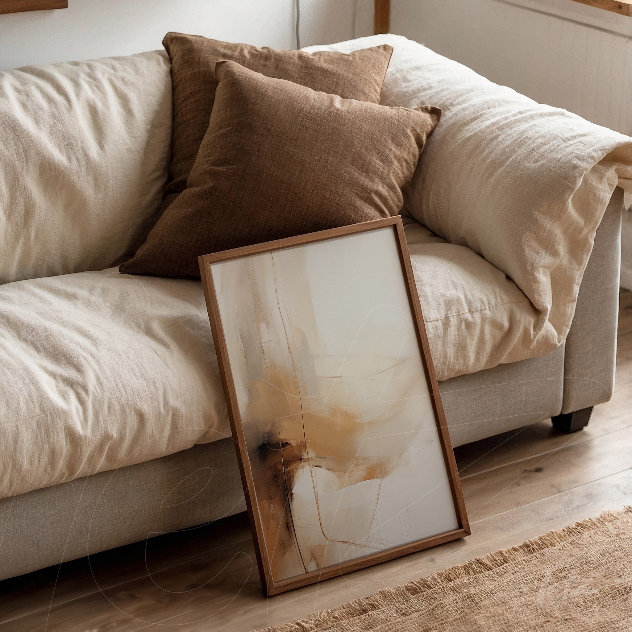 framed abstract wall art in neutral tones leaning against a sofa with brown cushions