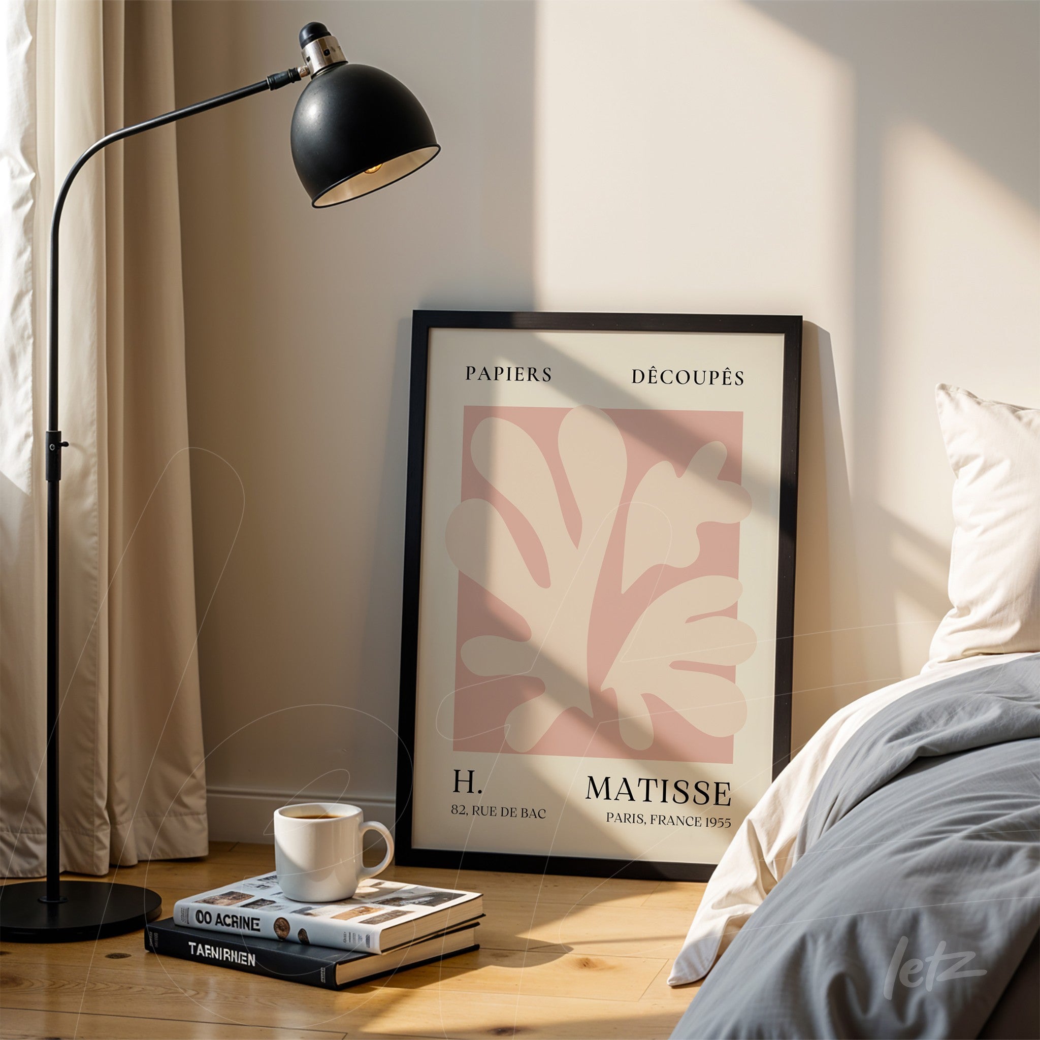 framed wall art featuring abstract leaf design in soft tones, leaning against a bedside table next to a bed, with a floor lamp in the background