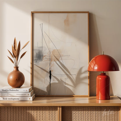 abstract artwork featuring fine lines in neutral tones displayed on a light wood table with a ceramic vase and a red lamp