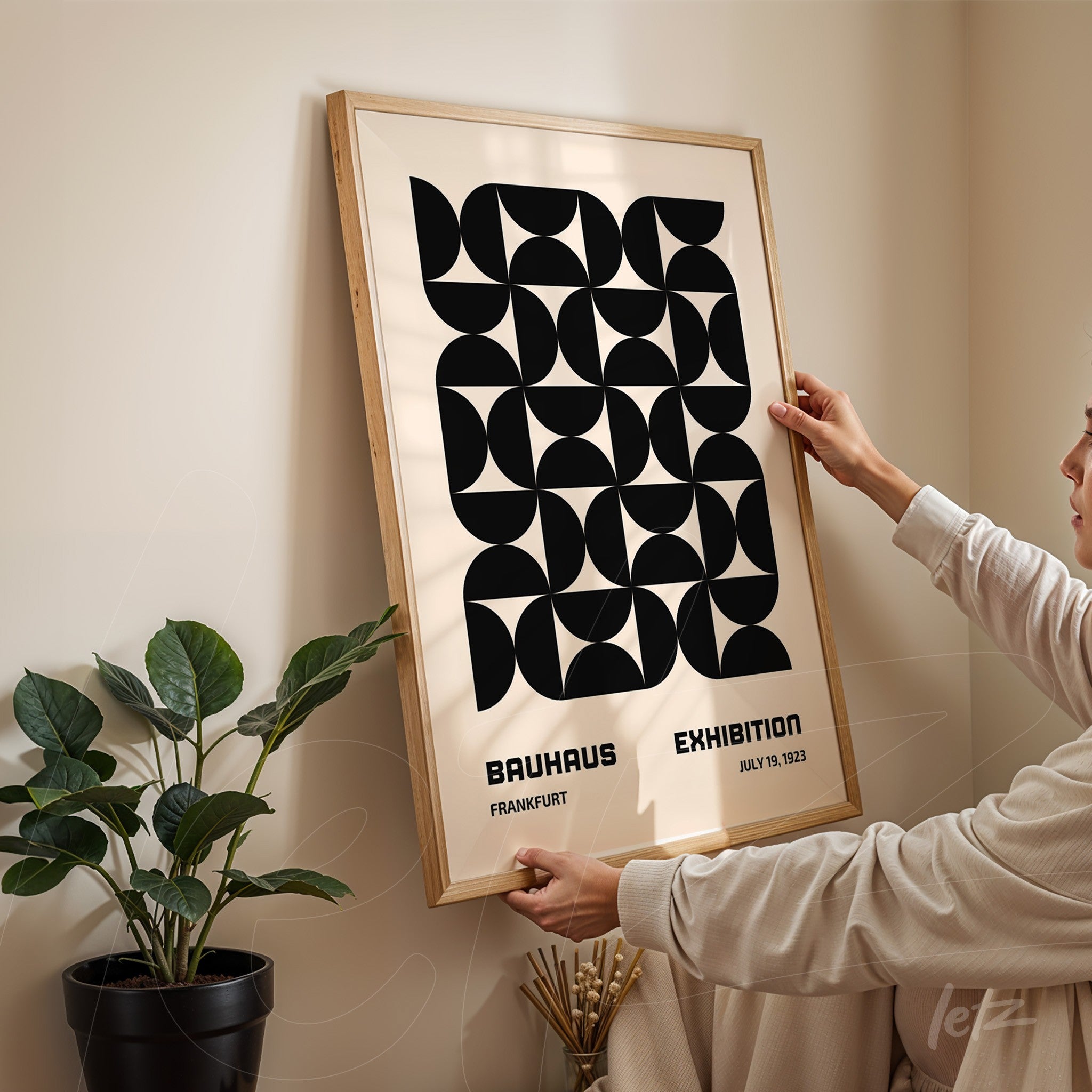 geometric black and white poster framed with light wood, displayed on a neutral wall