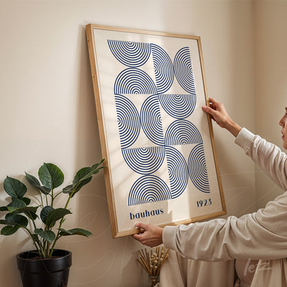 poster featuring bauhaus style geometric illustration, displayed in a light wood frame