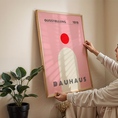 minimalist bauhaus art in pink and red tones with light wood frame
