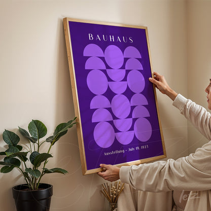 bauhaus style poster with geometric purple circles in light wood frame against neutral wall setting