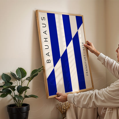 framed art piece with blue and white geometric design inspired by bauhaus, held against a corner wall