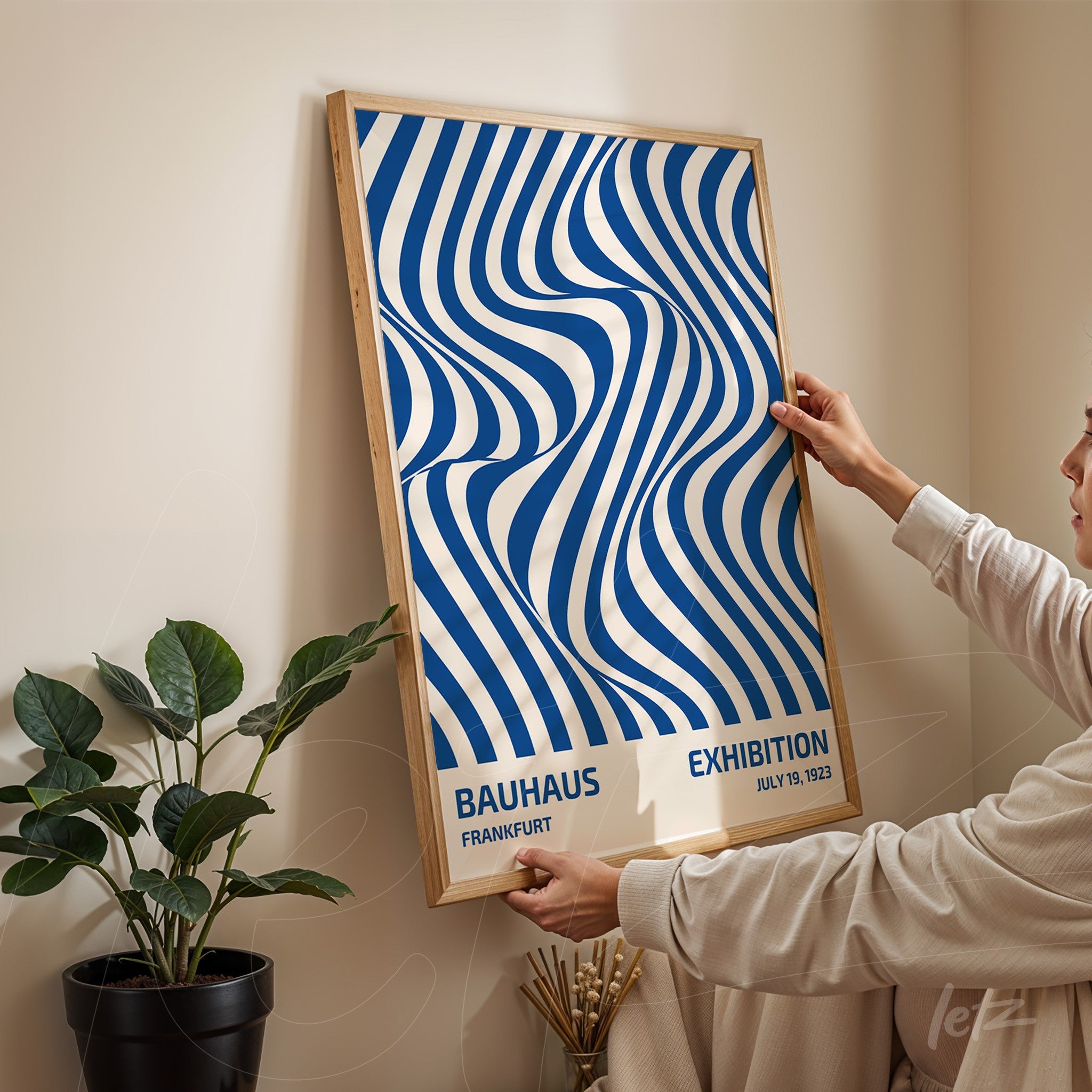 poster featuring abstract blue and white wavy lines art in a light wood frame being held by a person