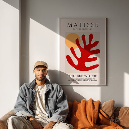 framed wall art featuring matisse's abstract shapes in red and yellow displayed above a sofa with an orange throw blanket
