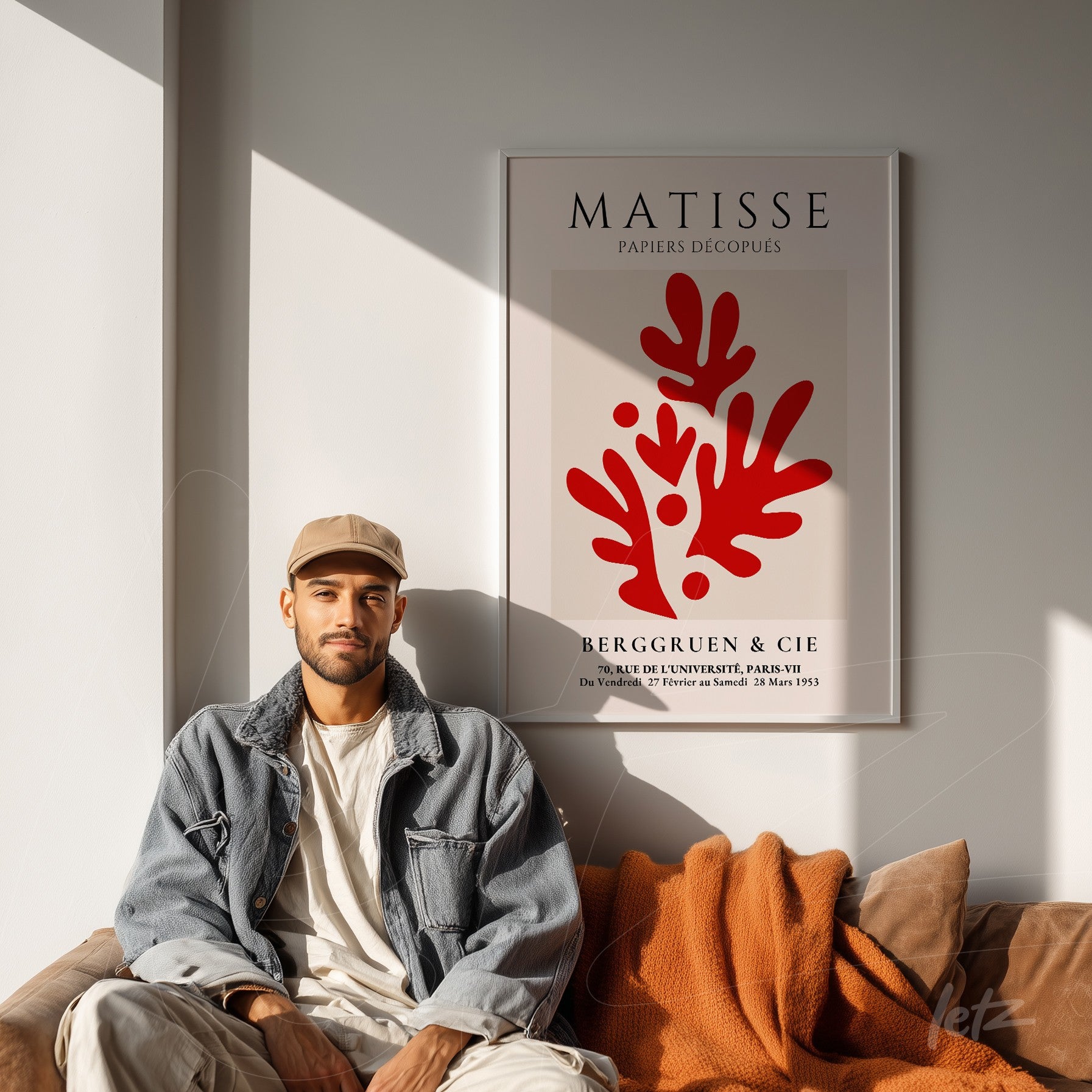 framed art by Matisse featuring organic red shapes, displayed on a wall beside a man in a cap and blue jacket