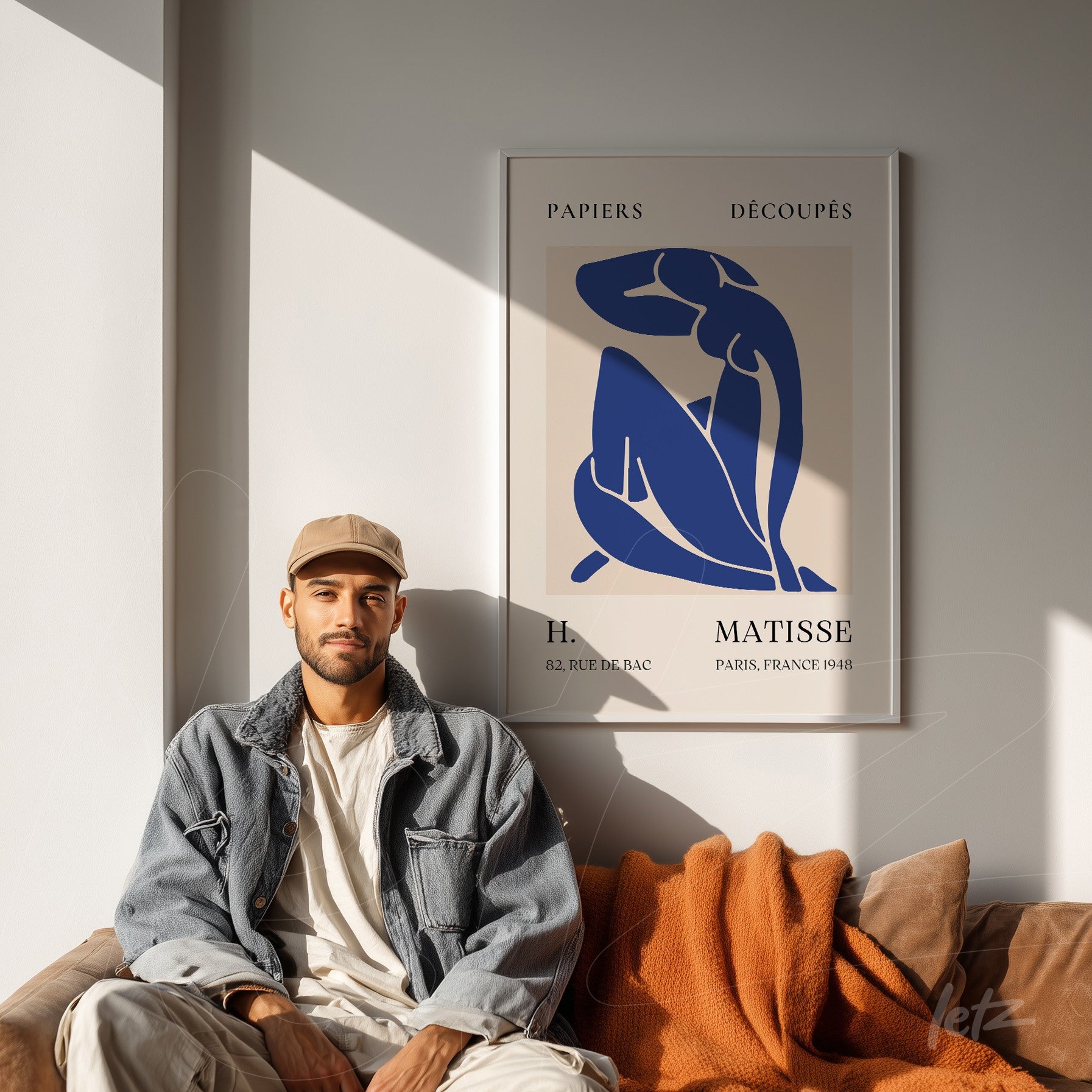 framed wall art by Henri Matisse displayed on a light wall with a person seated on a sofa