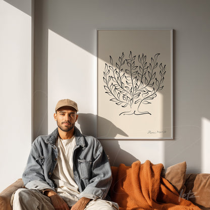 framed wall art with minimalist tree design displayed on neutral wall next to a casually dressed man