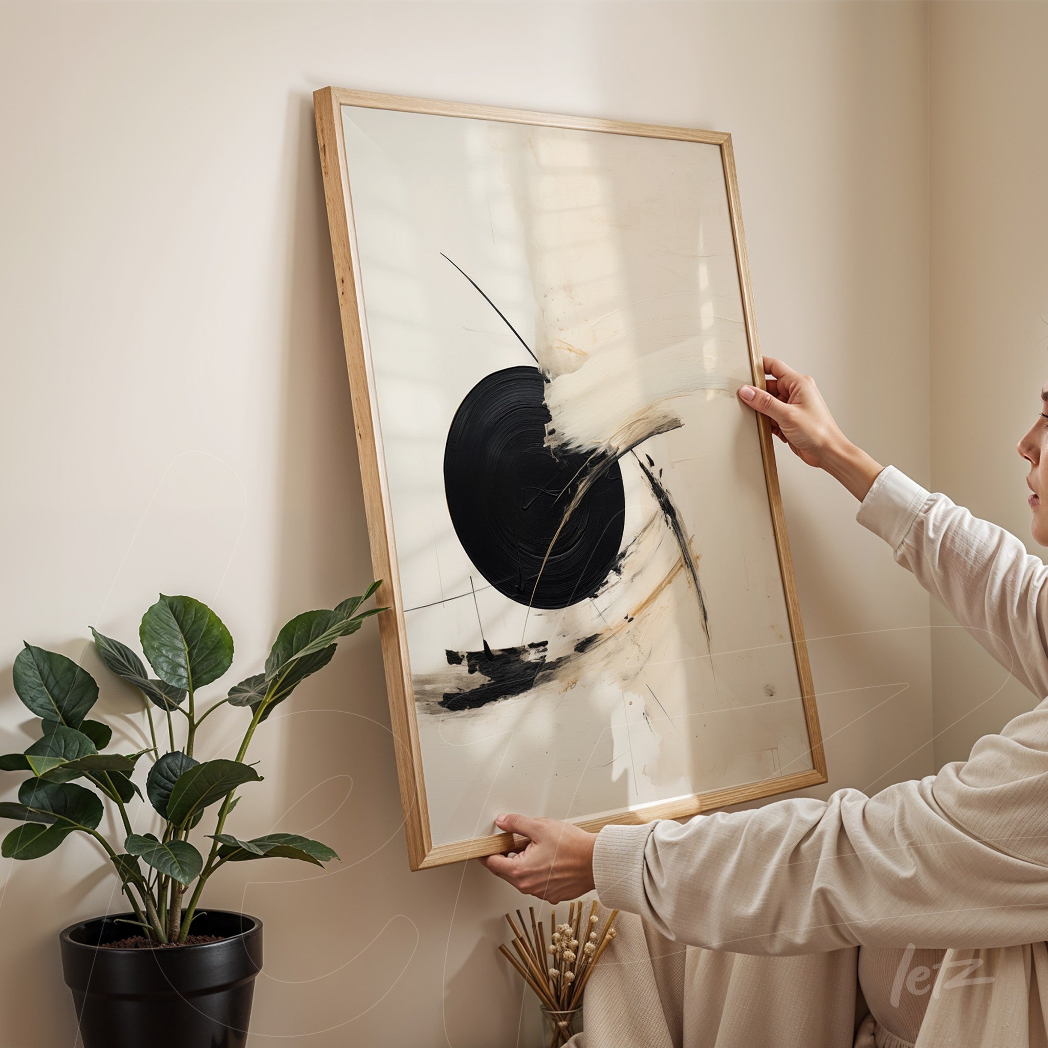 framed abstract art piece with light wooden frame displayed in a minimalist environment next to a potted plant
