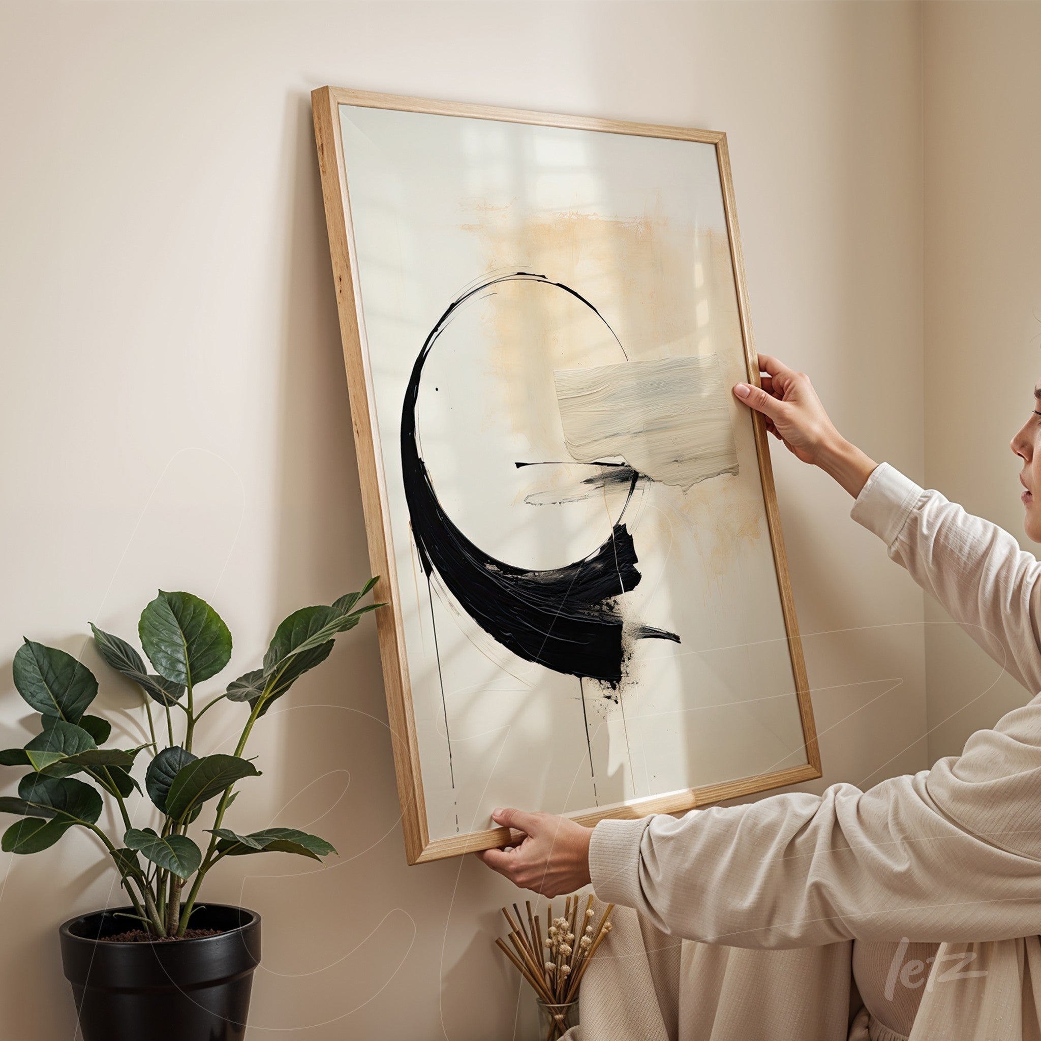 framed abstract wall art in black and white, held by a person in a bright room with a plant in the background