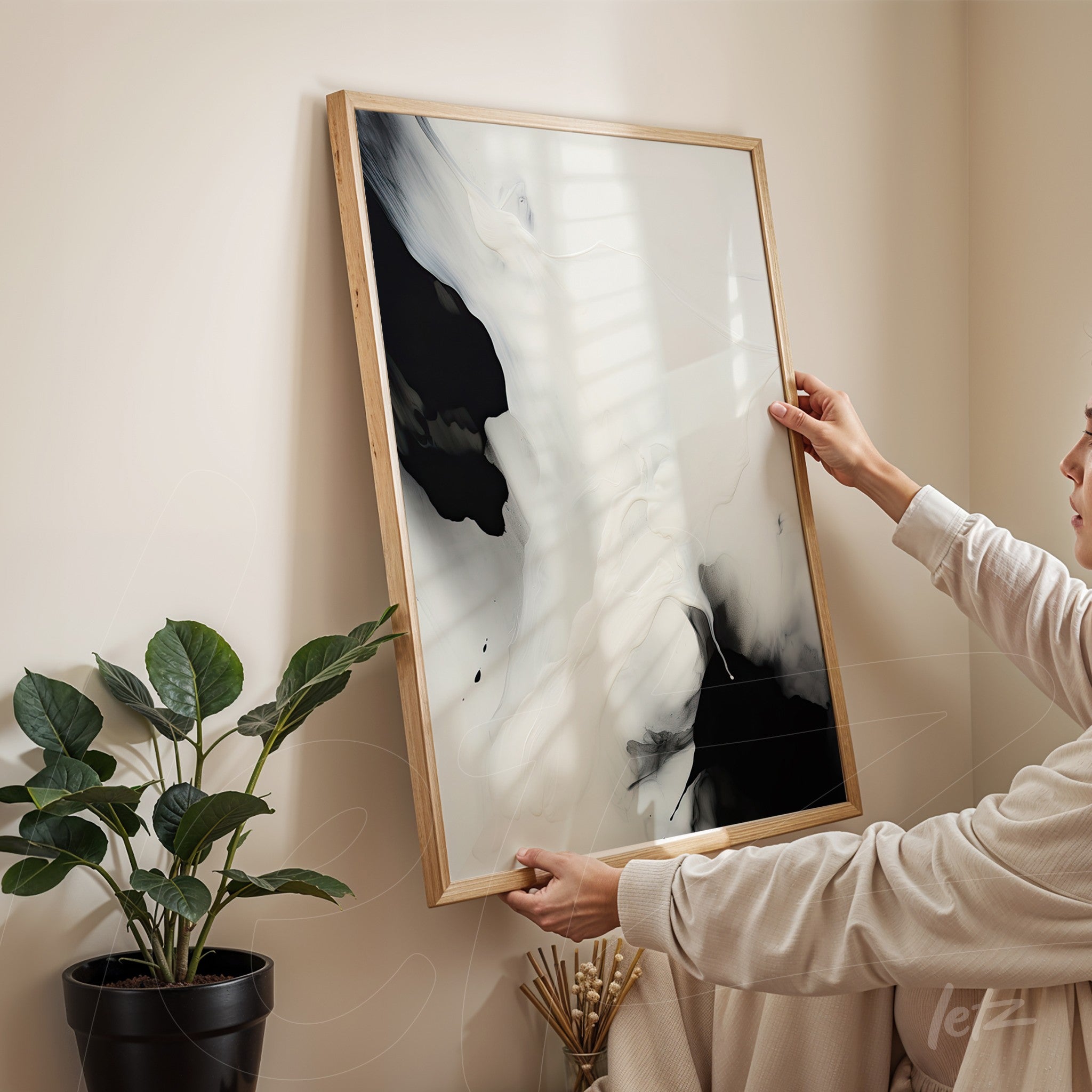 framed abstract artwork in black and white held by a person in an indoor setting