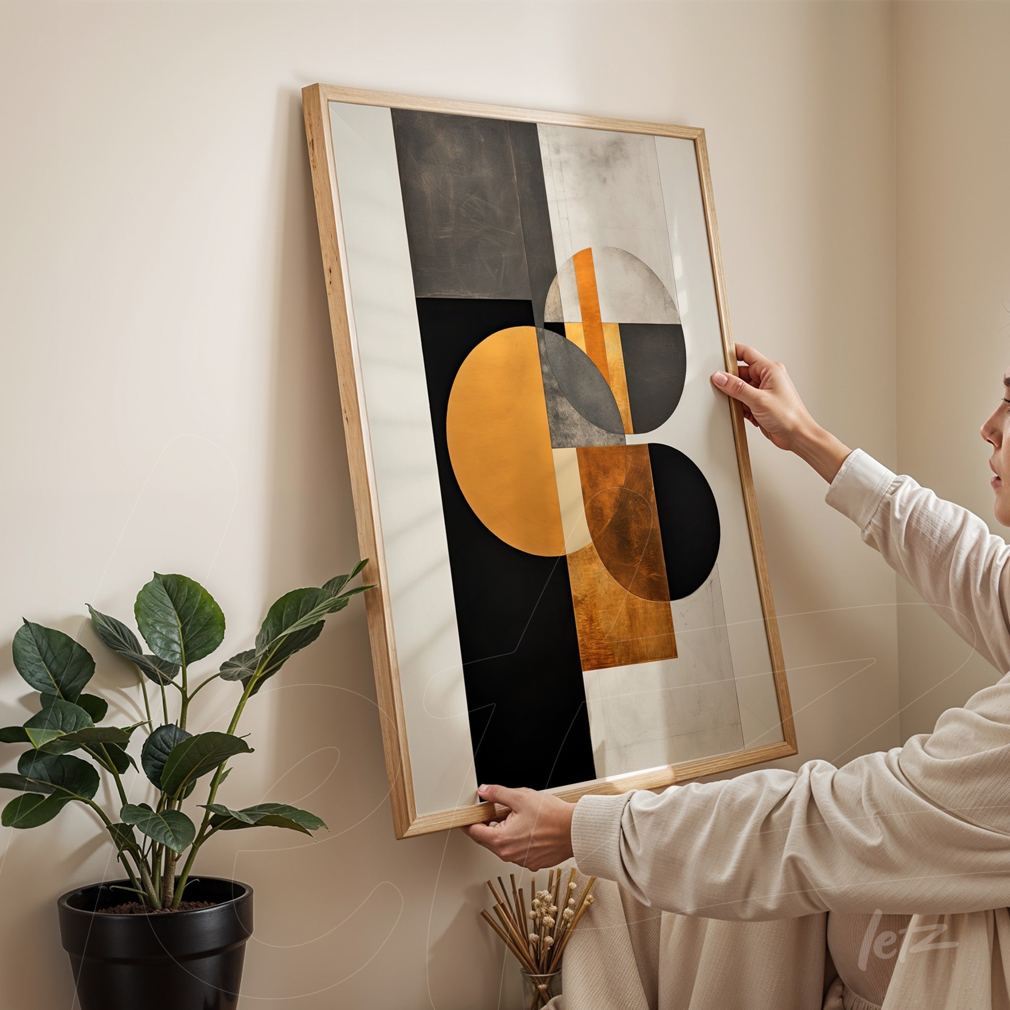 abstract wall art featuring black, gold, and white colors displayed in a light wood frame