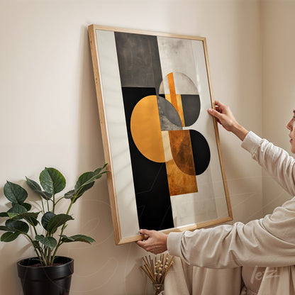abstract wall art featuring black, gold, and white colors displayed in a light wood frame