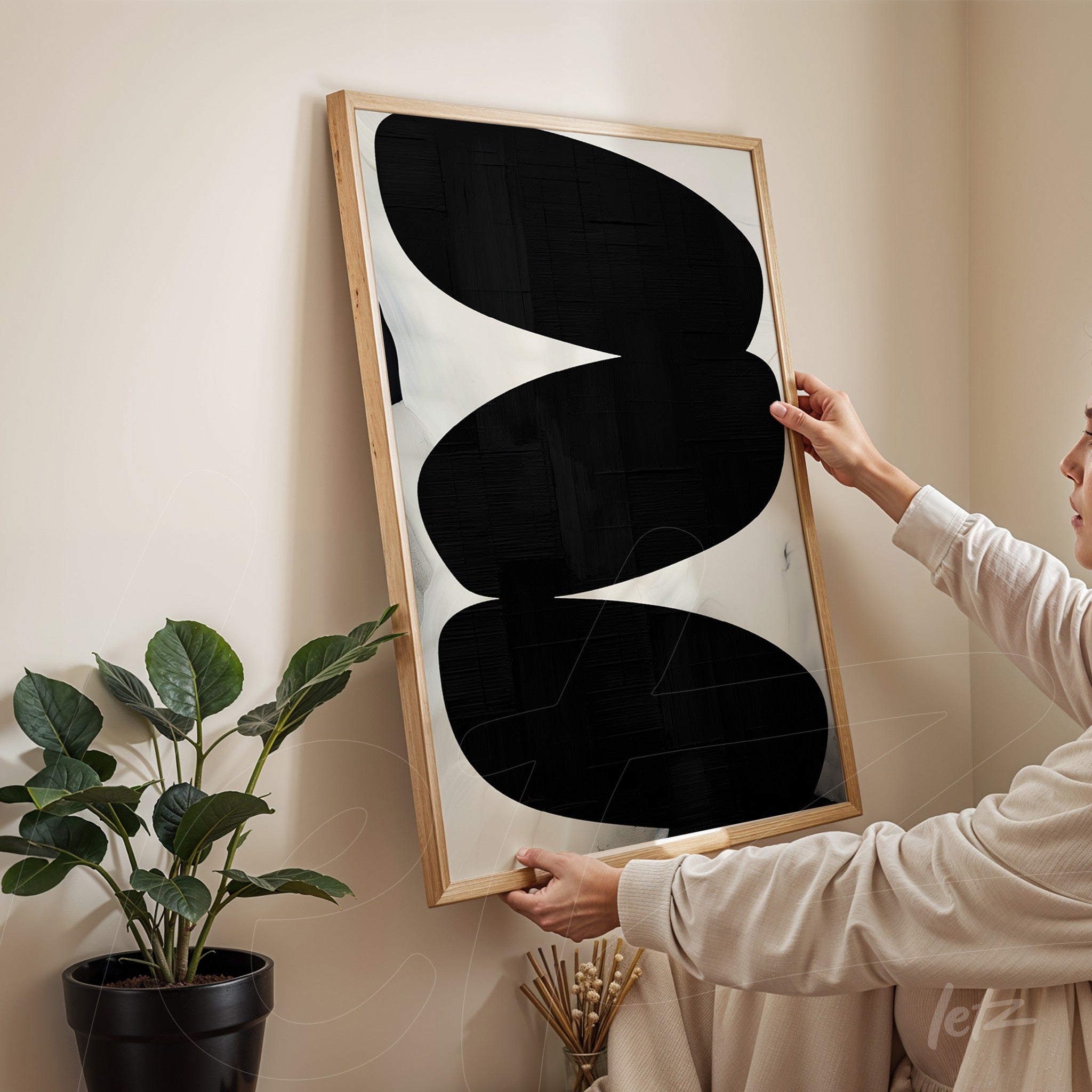 framed abstract wall art in black and white with light wood frame held by a woman in a neutral setting