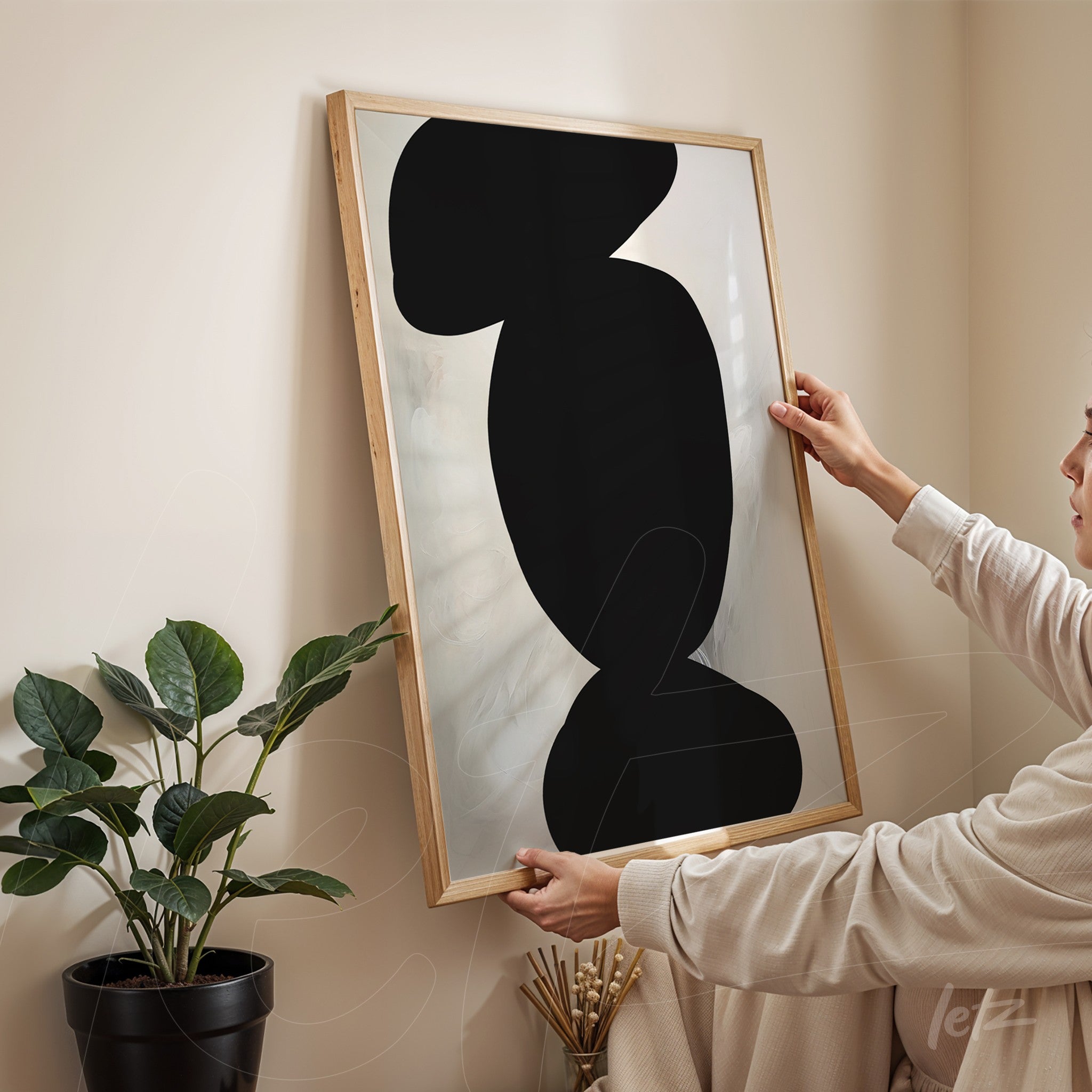 modern wall art featuring abstract black shapes on light background in light wood frame