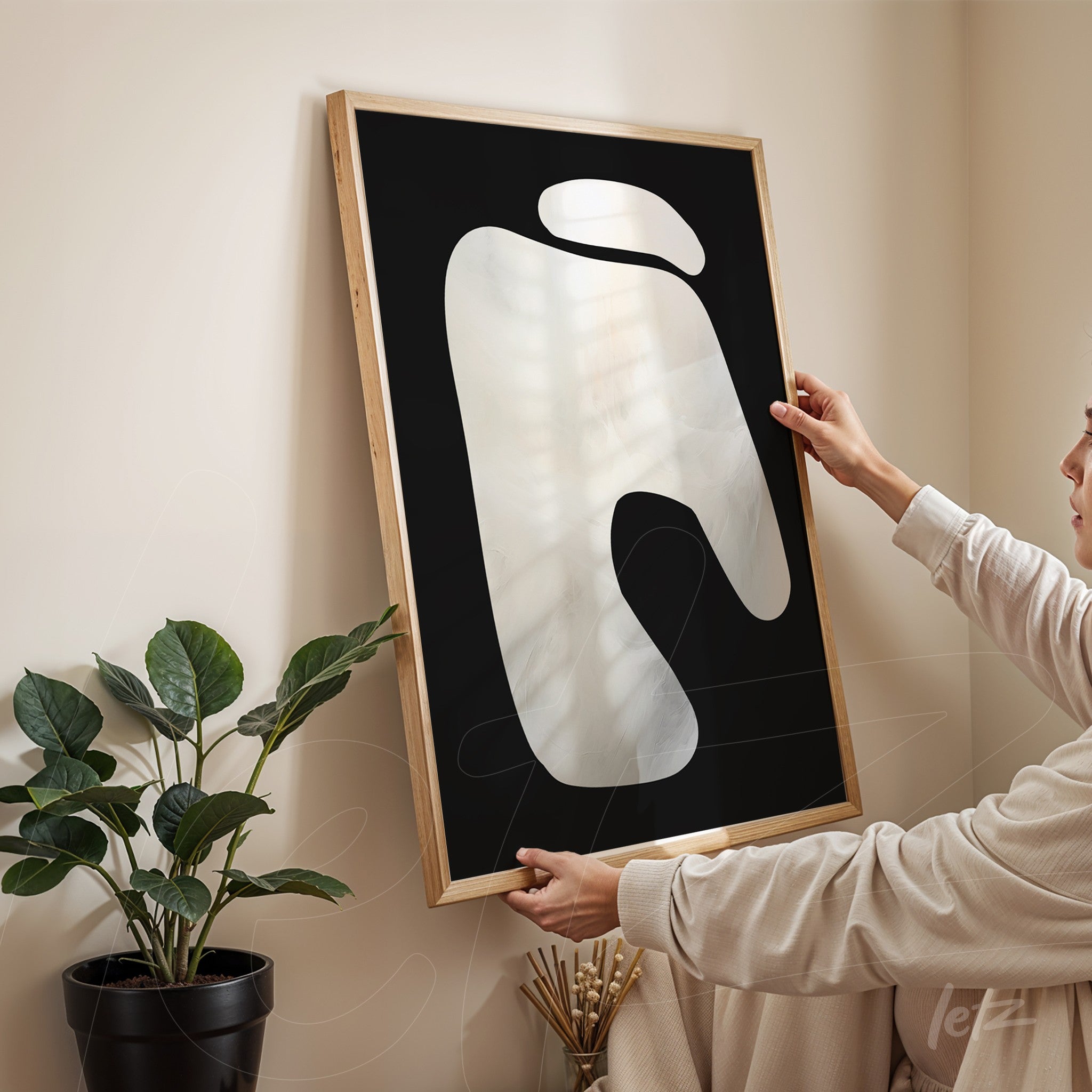 abstract wall art featuring fluid shapes in a light wood frame against a beige wall