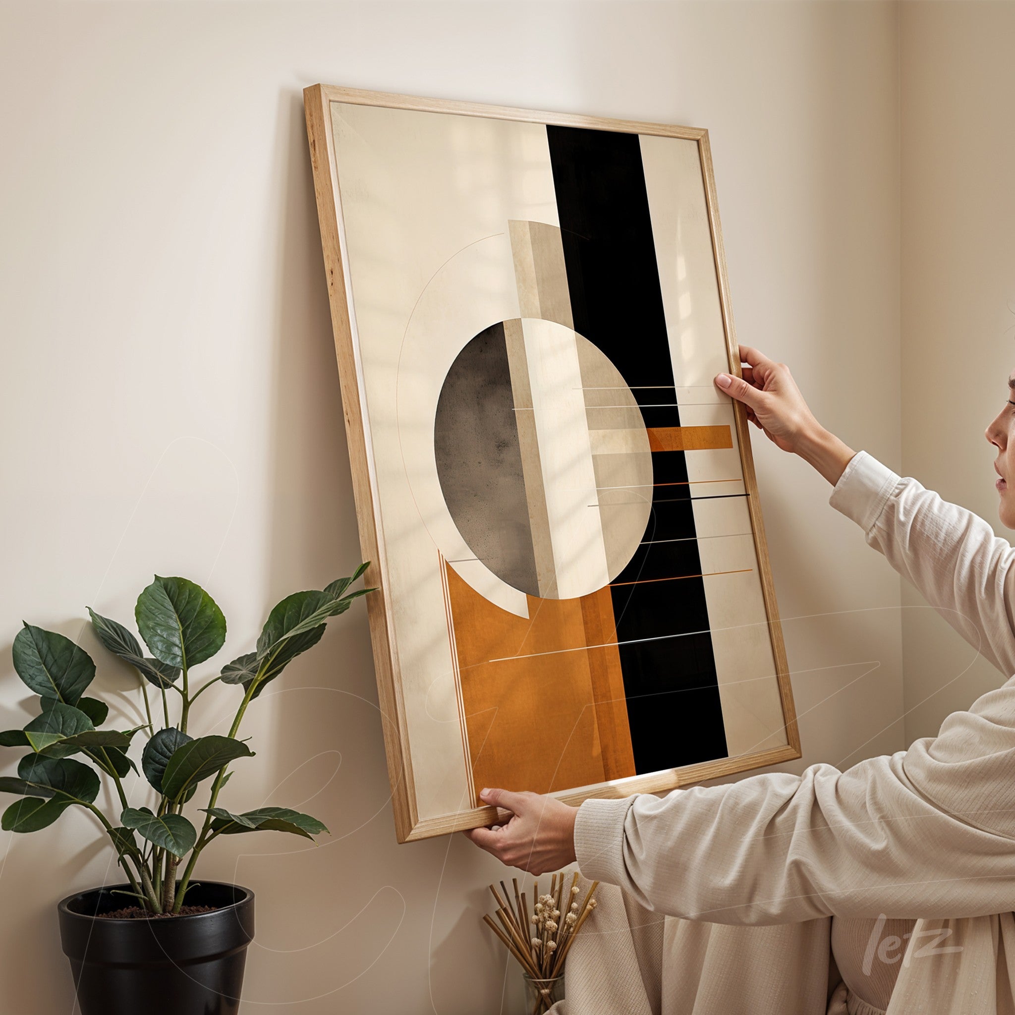 framed abstract artwork in earth tones held by a person against a neutral wall