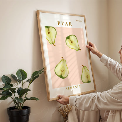 framed wall art featuring pear illustrations on a pink background held by a woman in an indoor setting