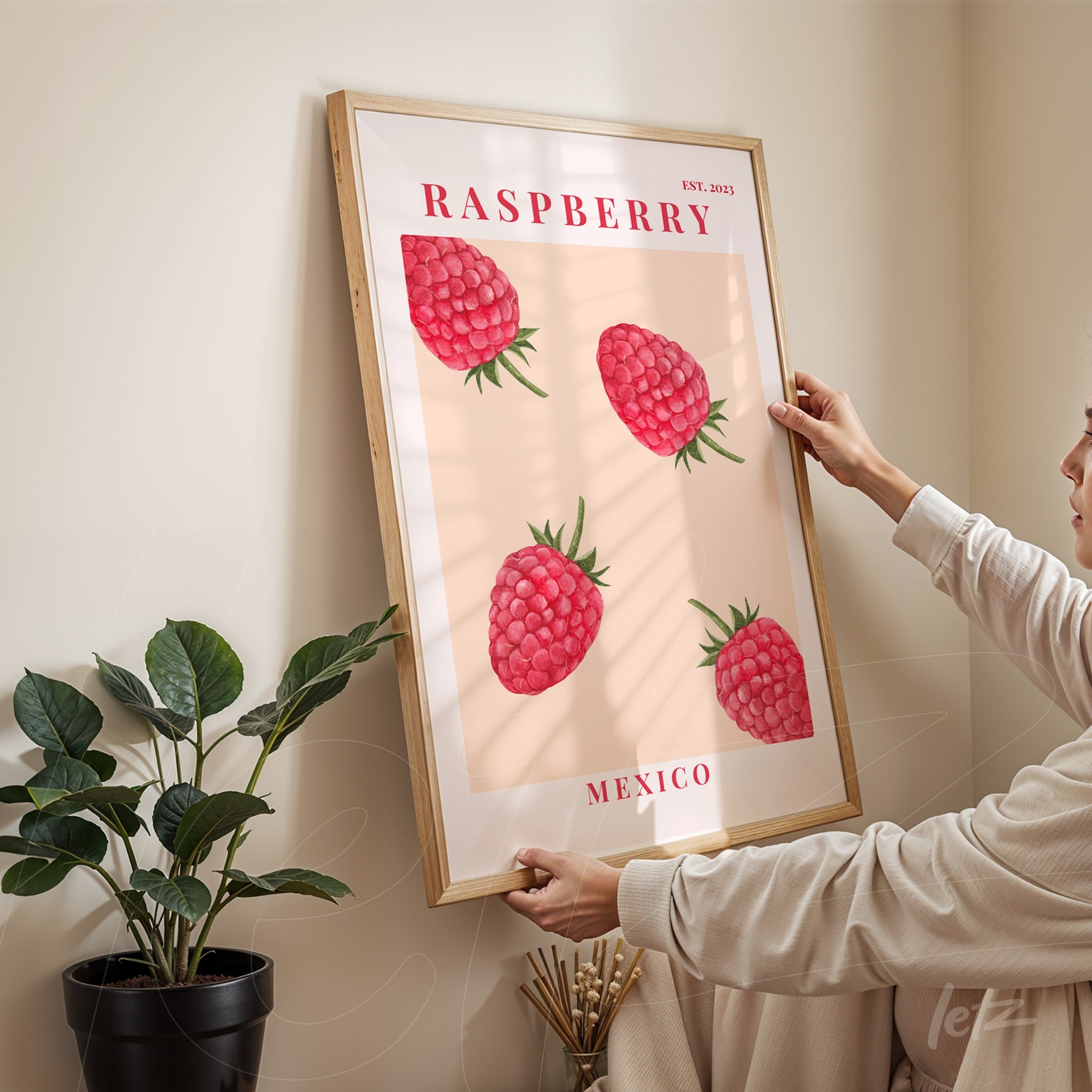 framed art featuring raspberries on a light background with a light wood frame
