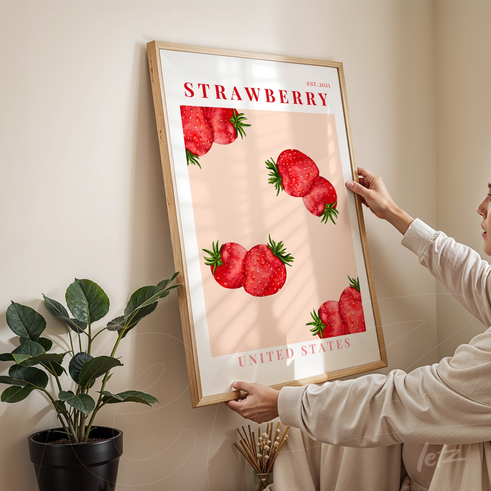 framed art print featuring strawberries on a pink background with a light wood frame