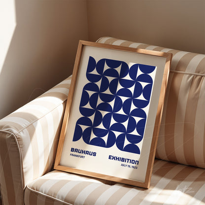 poster print with navy blue geometric design in natural wood frame, propped on striped sofa