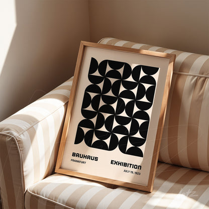 poster print with black geometric design in light wood frame, resting on striped sofa