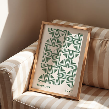 poster print with bauhaus style art in light wood frame, displayed on a beige striped sofa