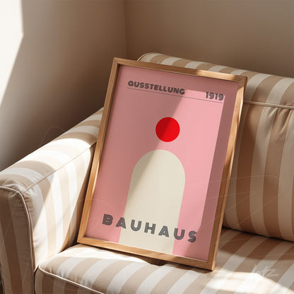 poster print with geometric Bauhaus style design in light wood frame, displayed on striped sofa