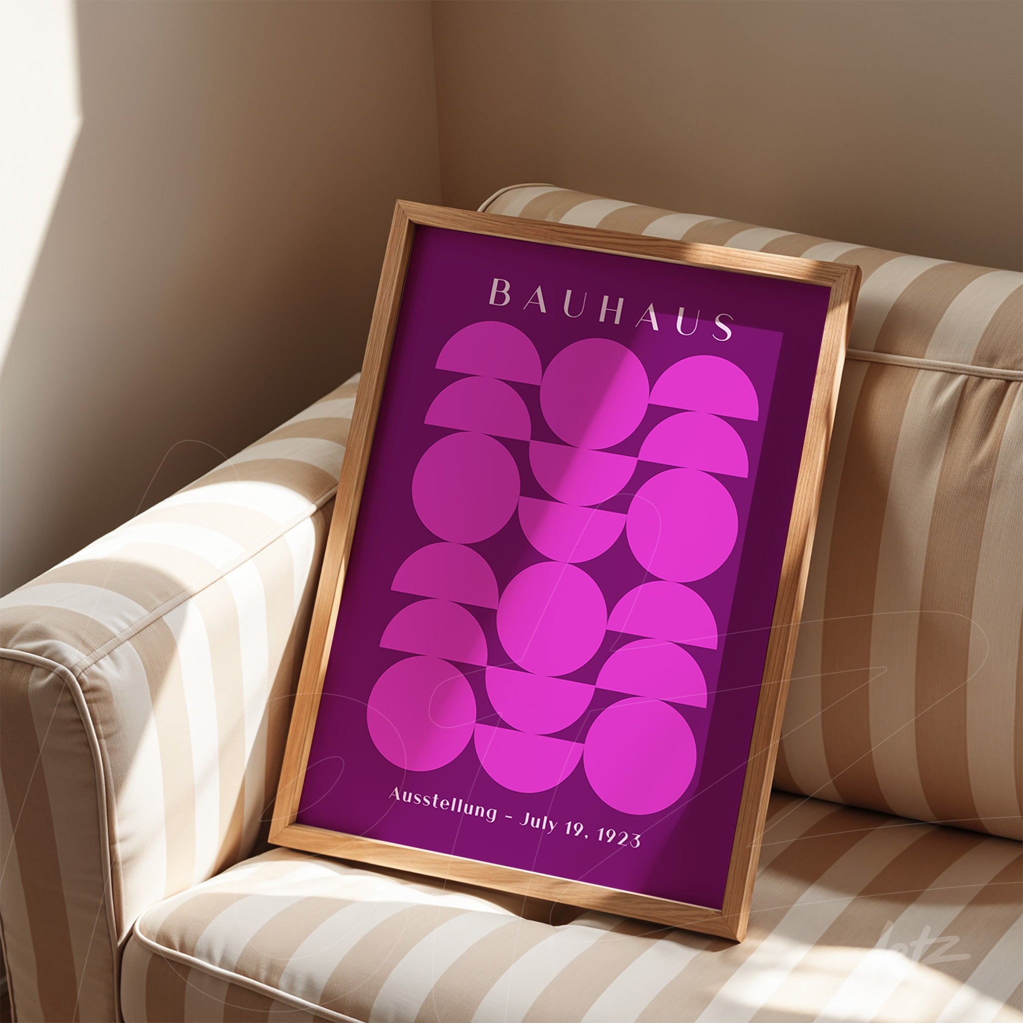 poster featuring geometric bauhaus style art in natural wood frame, placed on striped couch